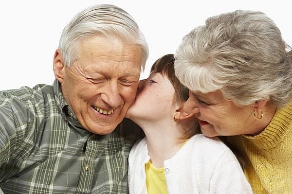 child kissing grandparents