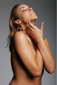 naked woman applying moisturizer
