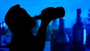 man drinking alcohol out of bottle