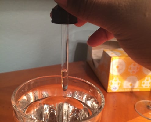 putting drops of adya clarity into a glass of water