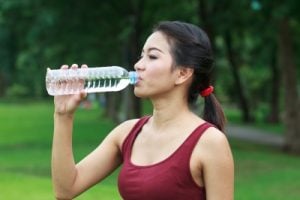 Woman drinking water outside for healthy skin