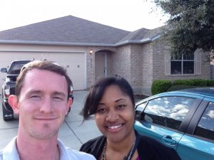 young couple taking a picture in front of house