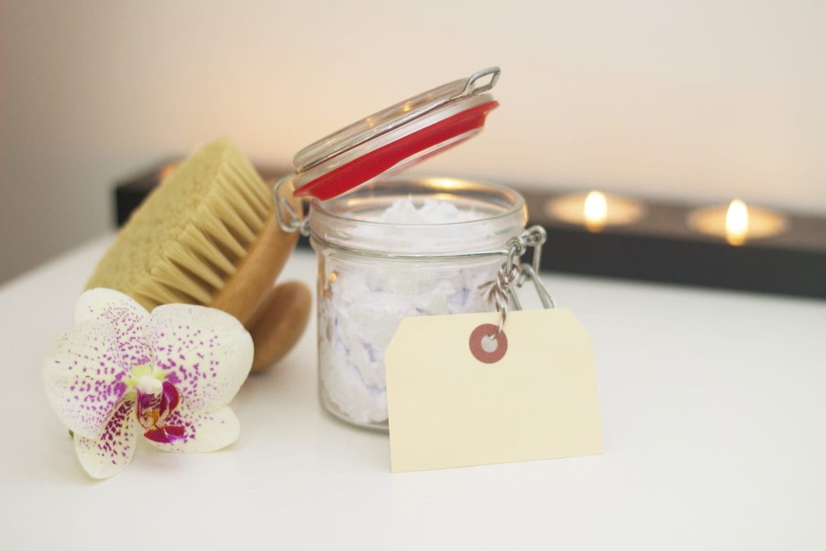 candle, brush, and flower with a jar of cream