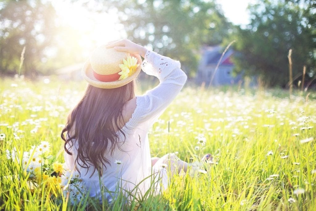 woman outside in daisy field with hat