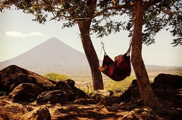 person sleeping in a hammock outside at the mountains - sleep tips for success