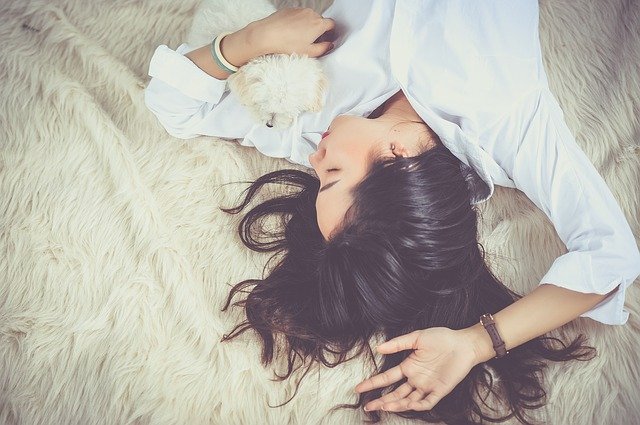 person sleeping on fuzzy carpet with dog - sleep tips for success