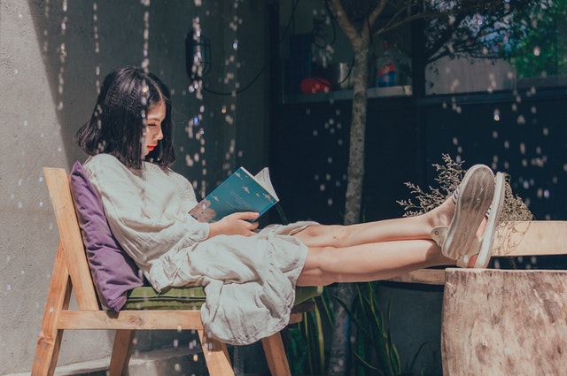 person relaxing outside and reading