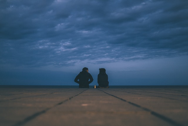 two people sitting down together outside