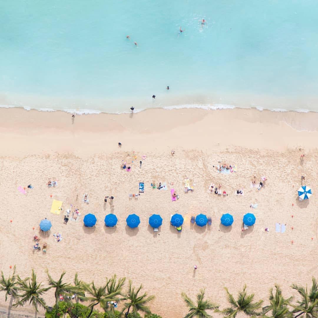 birdseye view of beach with blue umbrellas and people