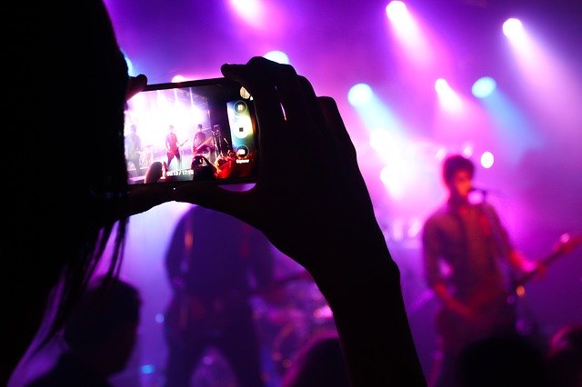 person taking a picture of a concert