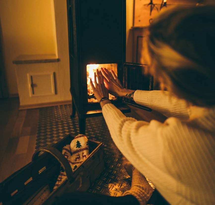 person in sweater sitting by fireplace