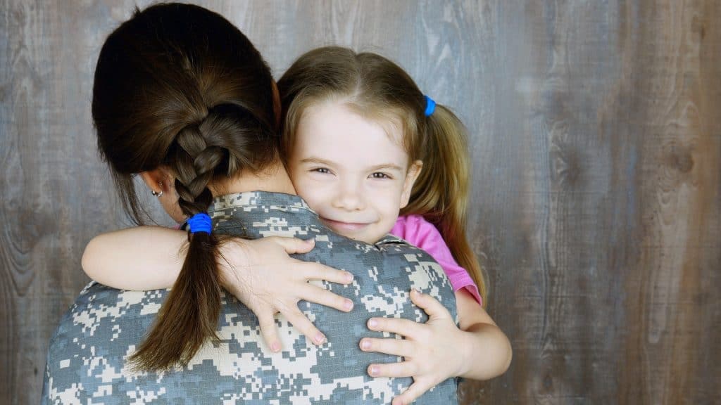 Military woman hugging young girl