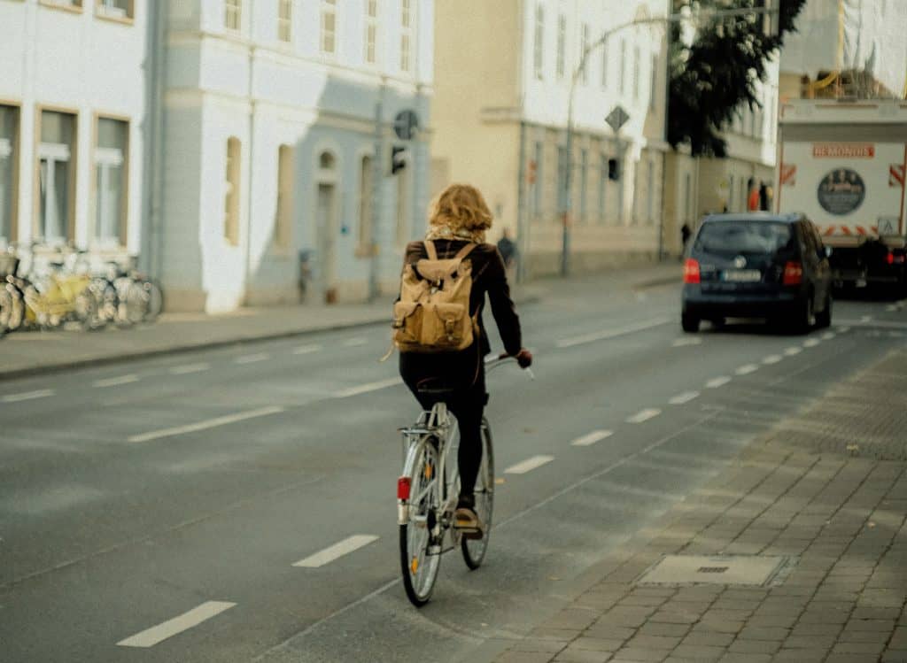 Woman riding a bicycle with a vehicle ahead of her
