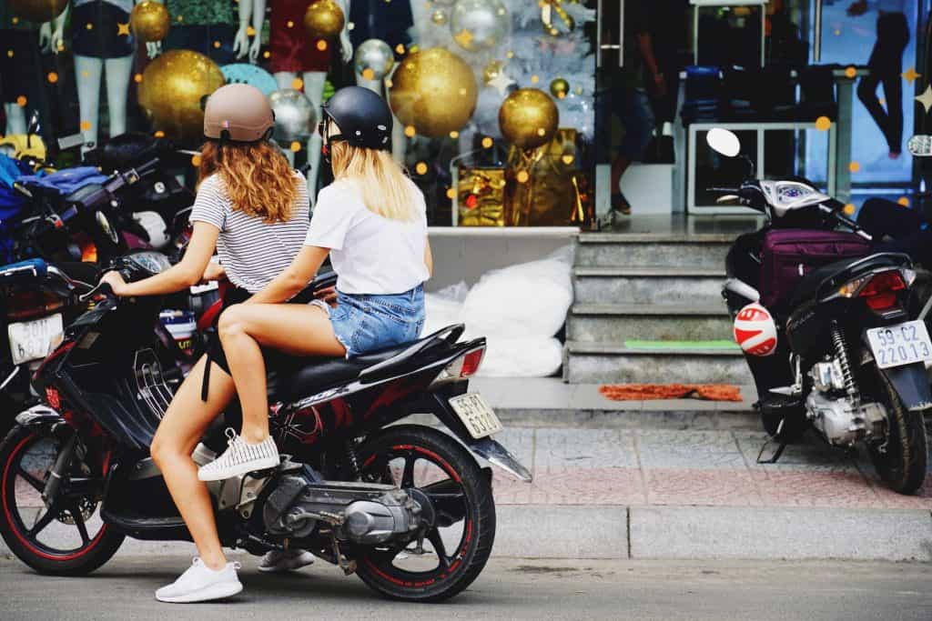 Two women on a vehicle (motorcycle)