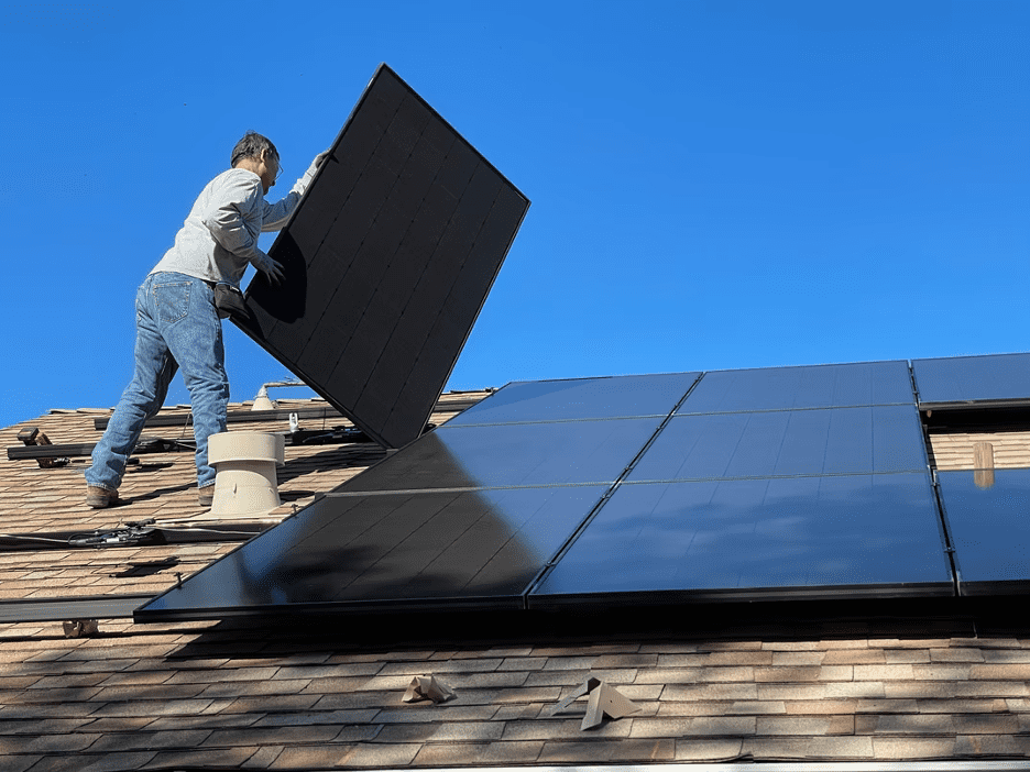 A man installing eco-friendly solar panels to his roof. 