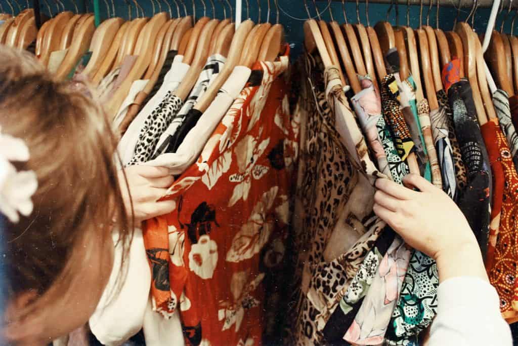 A woman looking through a rack of hanging clothes