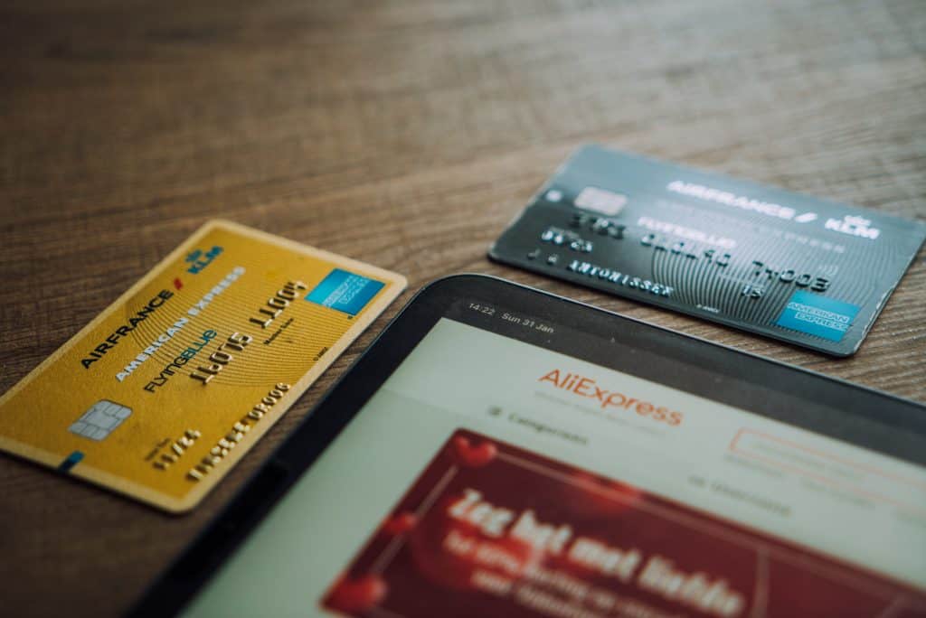 Two credit cards laying on table near an ipad 