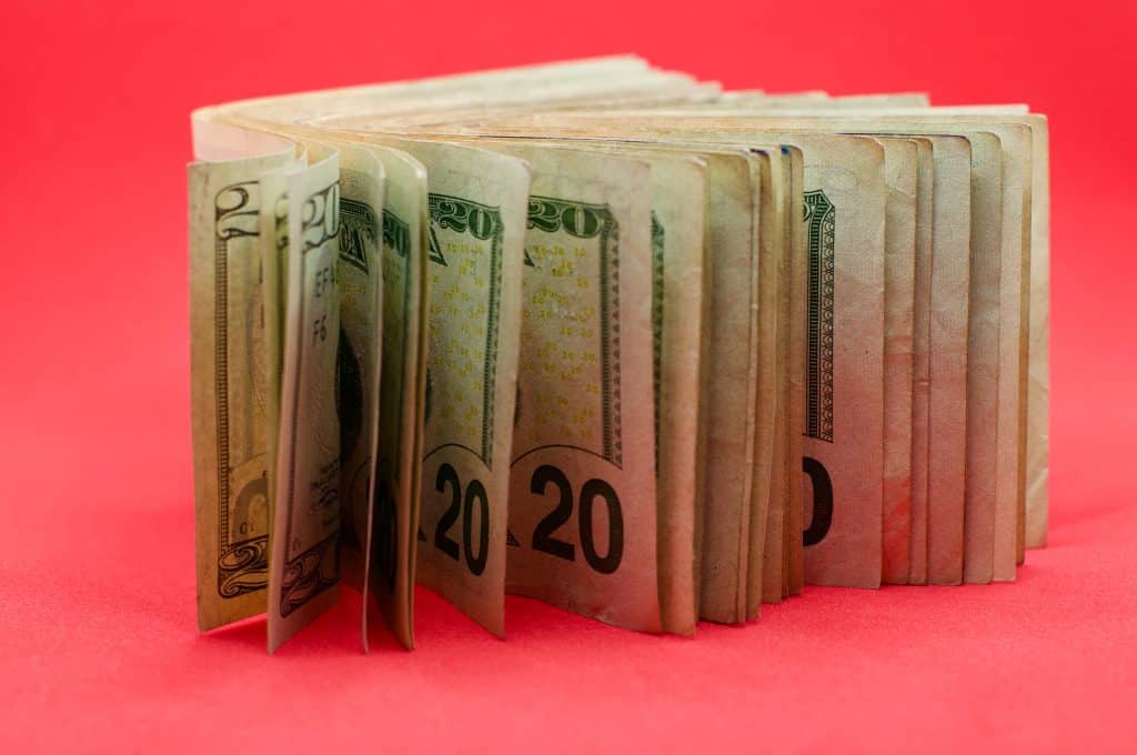 A stack of cash on a bright pink background 