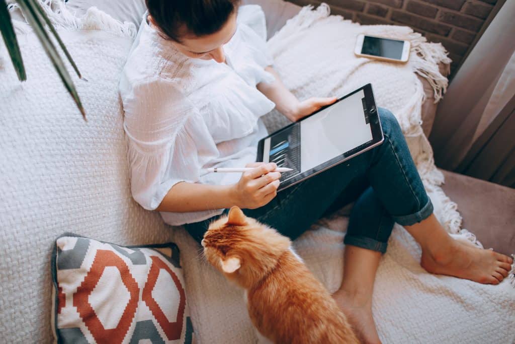 A woman working from home with her orange cat nearby