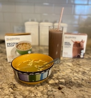 A mocha cream shake with chicken noodle protein soup on a kitchen counter 