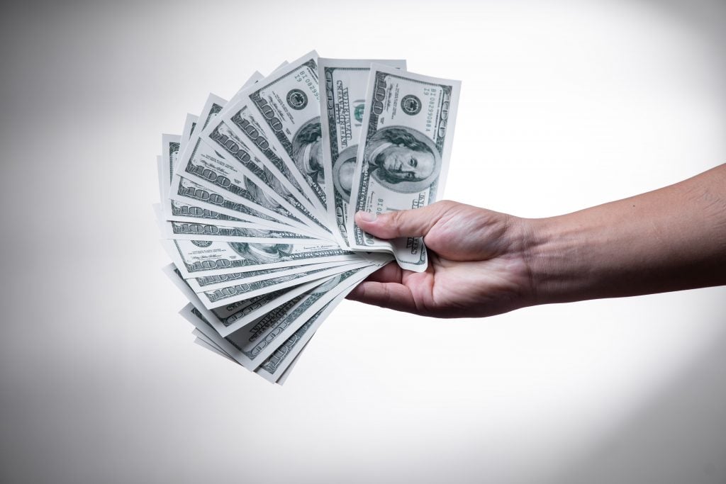A hand holding $100 dollar bills 