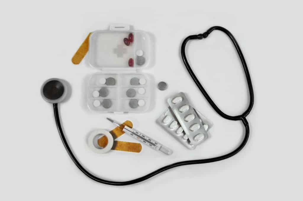 A stethoscope and a variety of pills laid out on a table