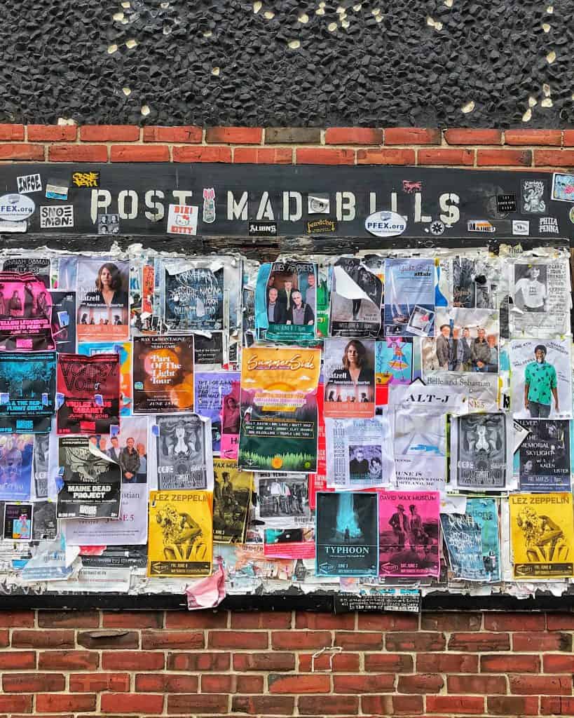 A wall of flyers hanging  on brick
