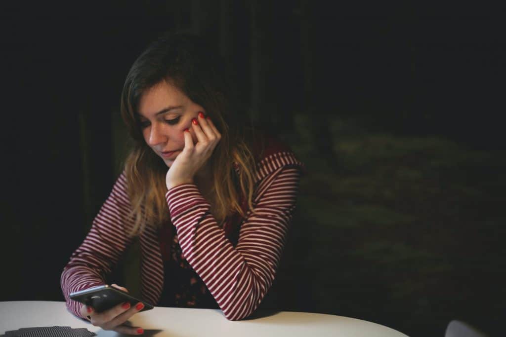 A woman sitting at a table and looking at her phone