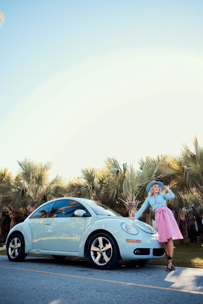 A woman standing next to her blue VW beetle 