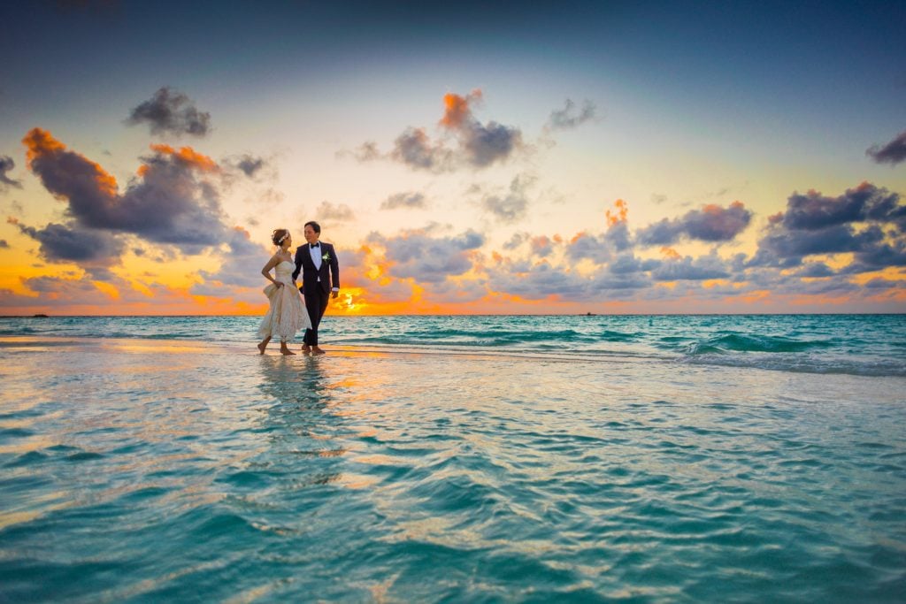 A couple taking wedding photos at the beach representing perfect beach wedding destinations in the US.