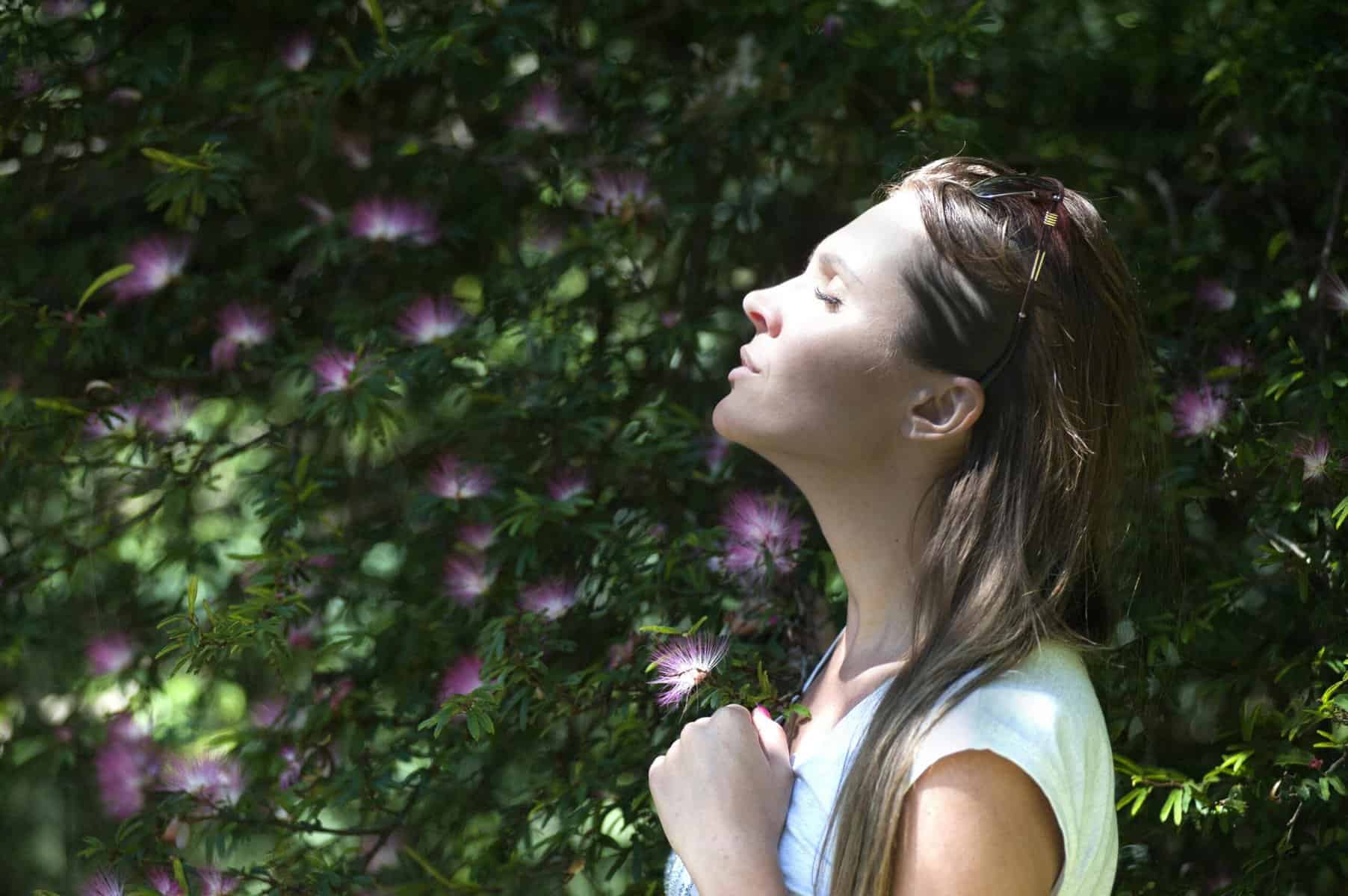 a woman standing in front of a tree with her eyes closed